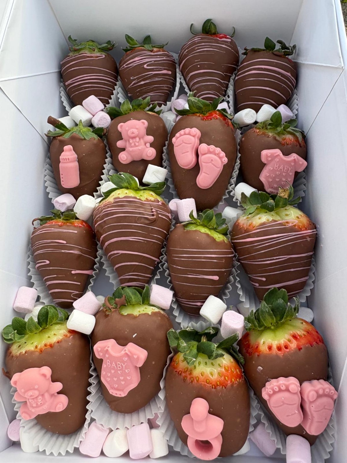 Chocolate strawberry box with pink baby feet, teddy bears, bottles and baby clothes decorations